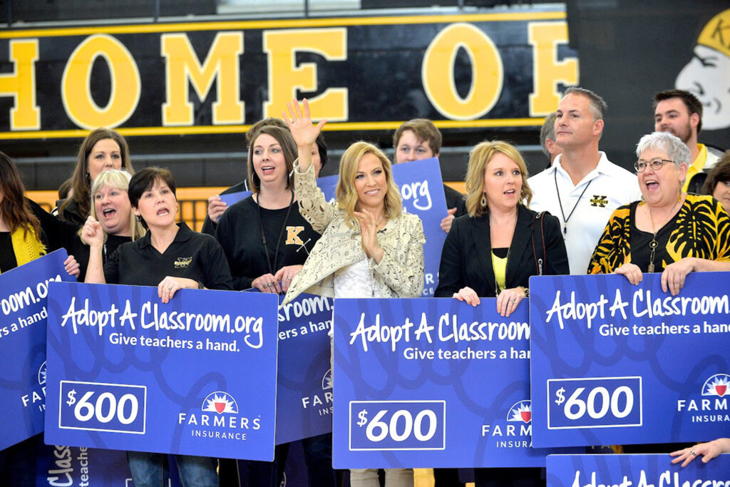 Sheryl Crow standing with teachers who are each holding a giant AdoptAClassroom.org check for $600.
