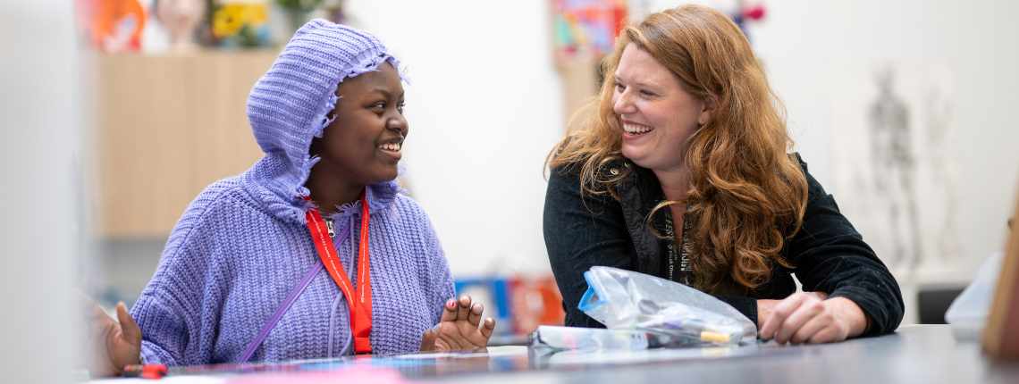 A student and a teacher working together and smiling